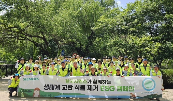 한국지멘스 임직원들이 22일 서울 여의도 샛강 생태공원 일대에서 ‘생태계 교란 식물 제거 ESG 캠페인’을 진행한 뒤 기념 사진을 촬영하고 있다